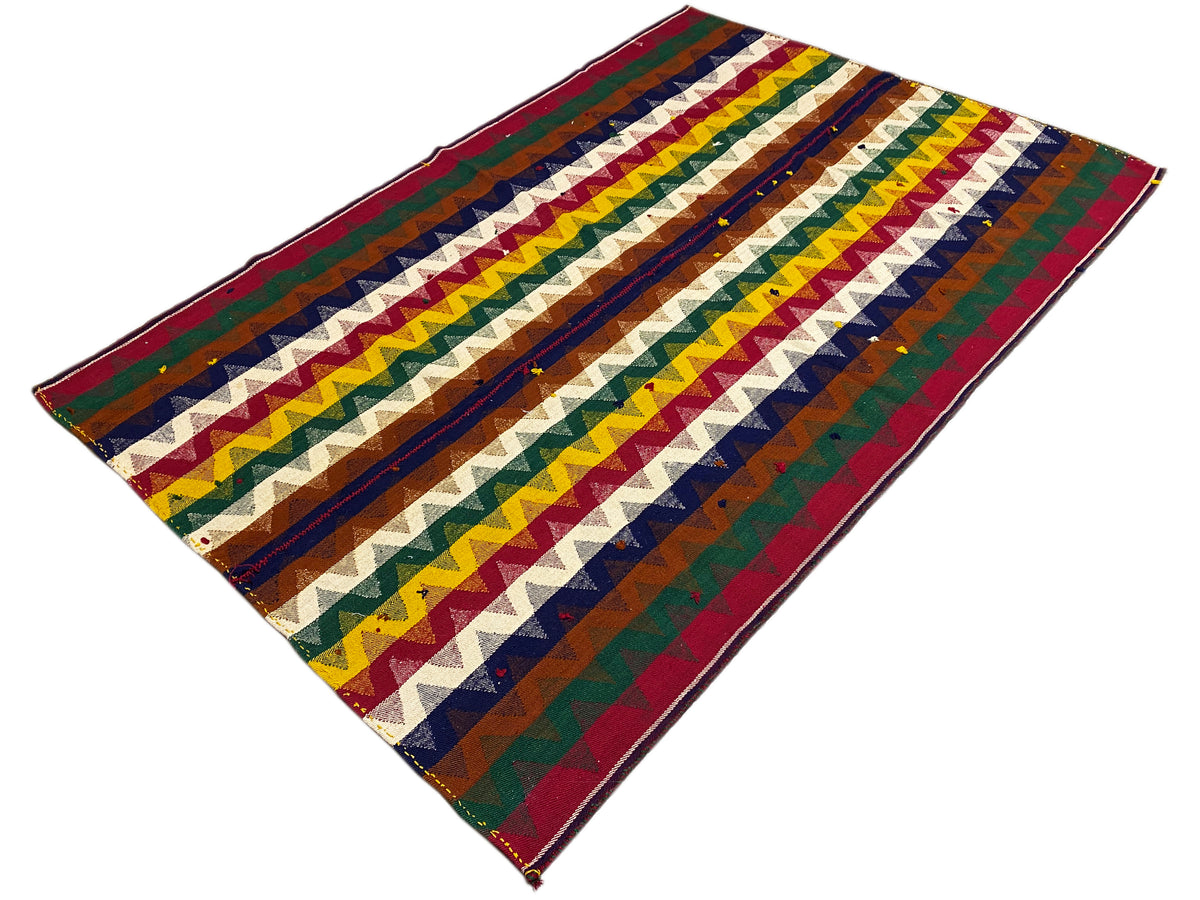 Tappeto Jajim in prospettiva diagonale con strisce Chevron colorate e motivo a zigzag