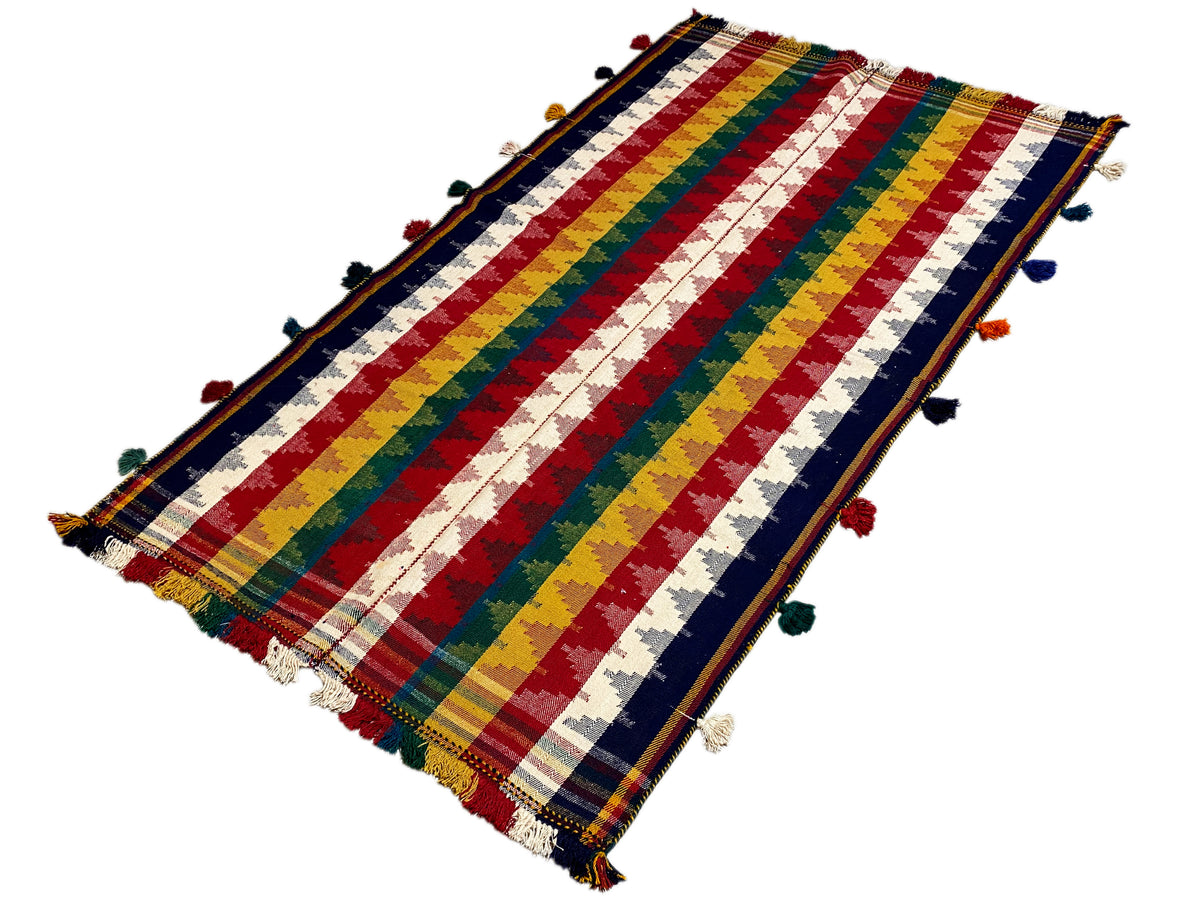 Tappeto Jajim piegato con strisce dall’effetto diagonale e nappe colorate