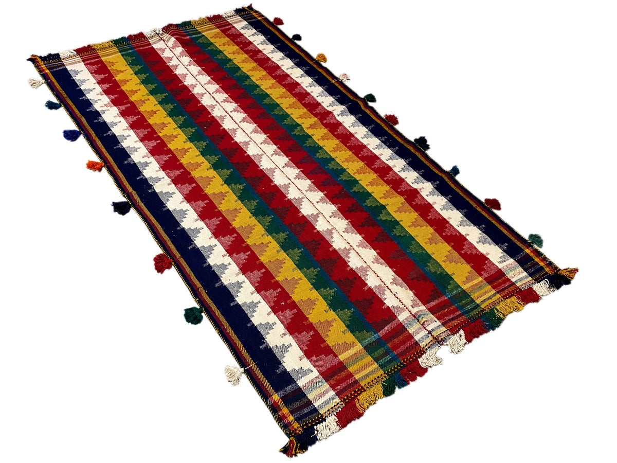 Tappeto jajim visto dall’alto di sbieco: strisce multicolori, nappe agli angoli