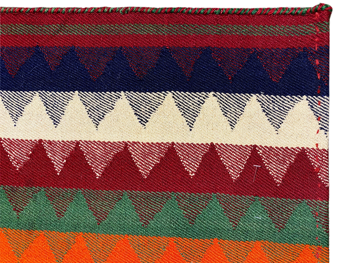 Primo piano di un tappeto Jajim: strisce colorate con bordi a zigzag e struttura tessuta