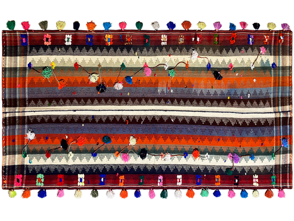 Tappeto a strisce multicolore con motivi floreali, bordo decorativo e frange