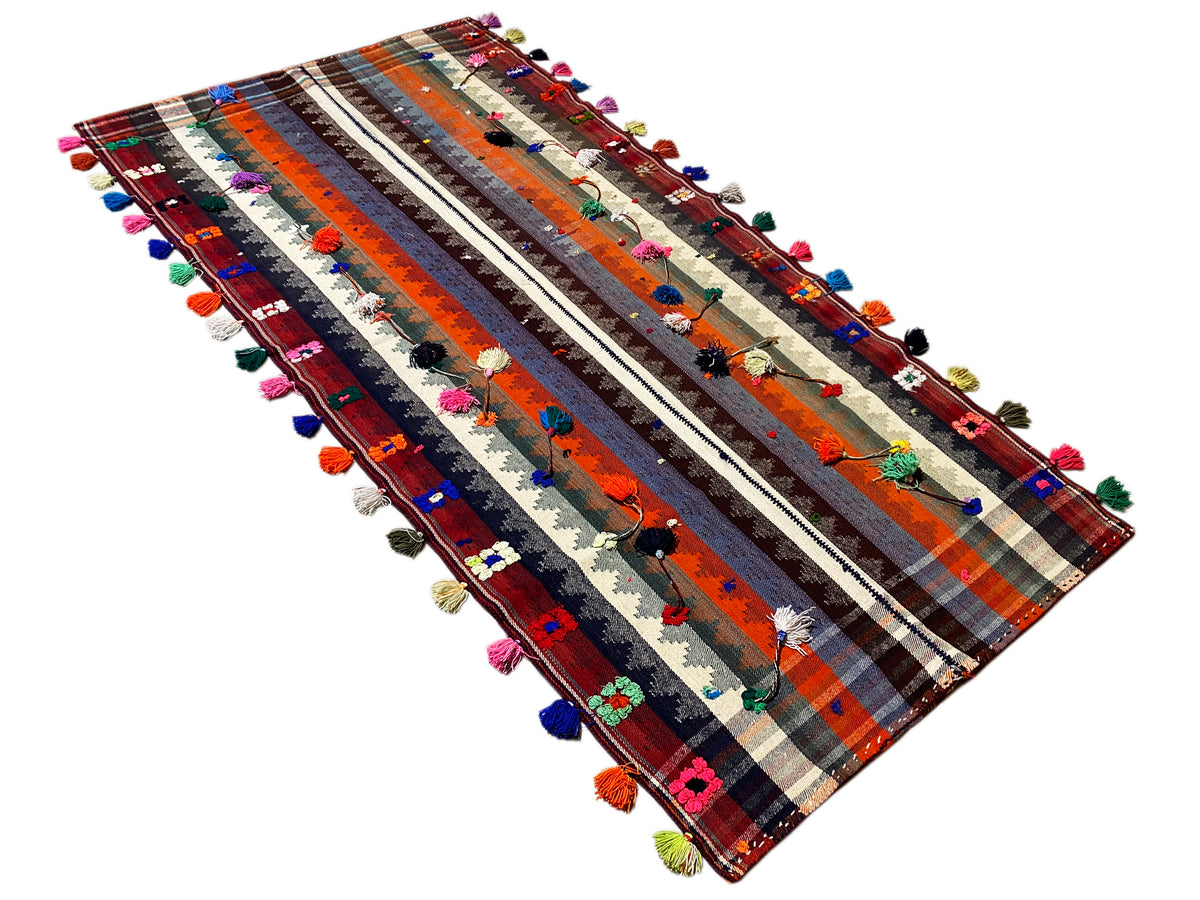 Tappeto jajim visto in diagonale, con strisce e nappe colorate sui bordi