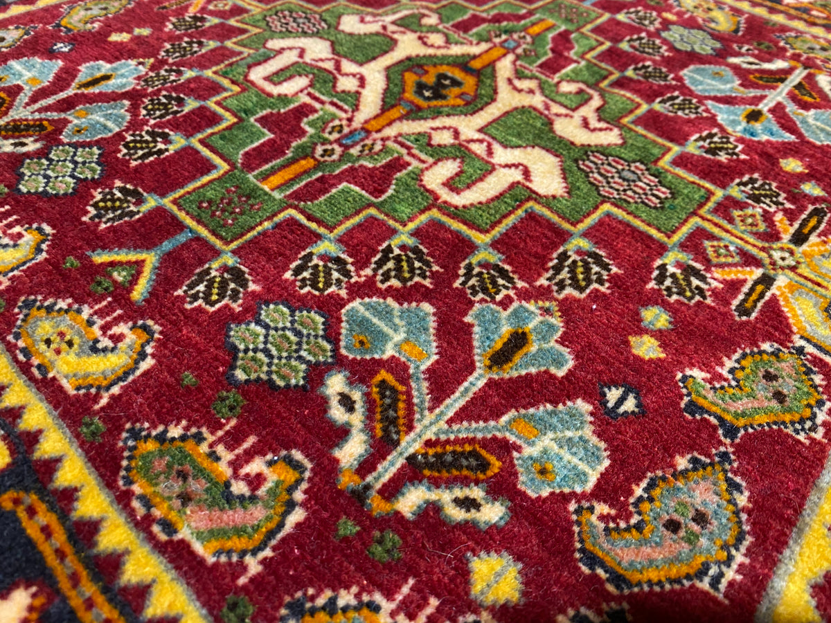 Primo piano del tappeto Poshti 61x61 cm, campo rosso con motivi verdi e blu