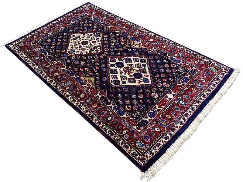 Tappeto blu scuro con bordo decorato rosso, diversi medaglioni, frange