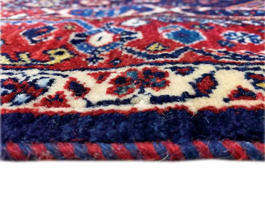 Primo piano del bordo di un tappeto con ornamenti colorati e pelo soffice