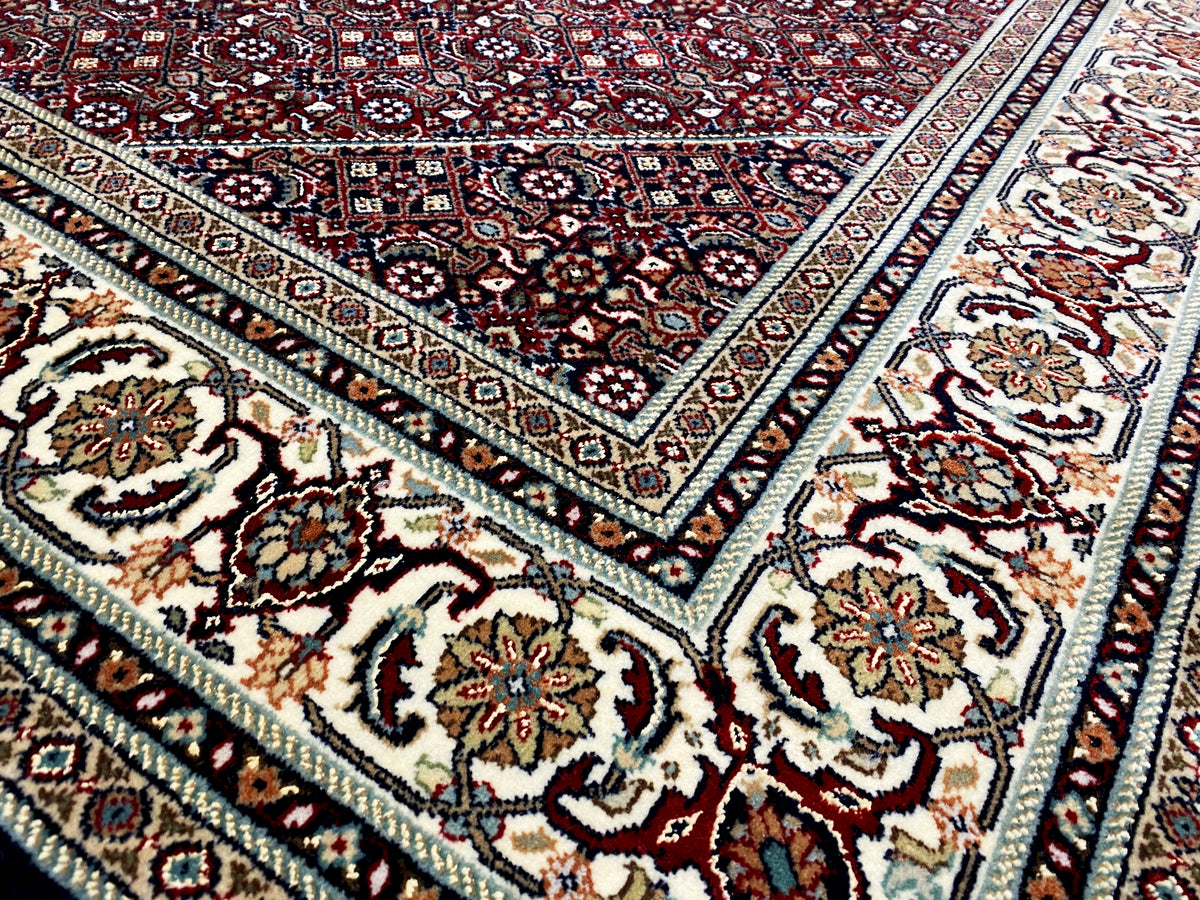 Tappeto con motivo ornamentale, base scura nei toni del rosso, del blu e del crema