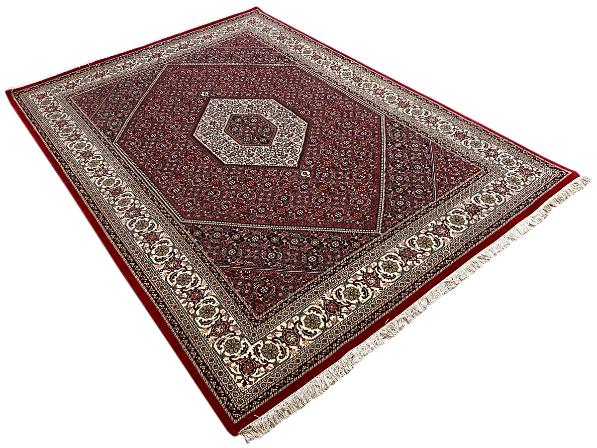 Tappeto Bidjar rosso disteso, con medaglione al centro, bordura e frange