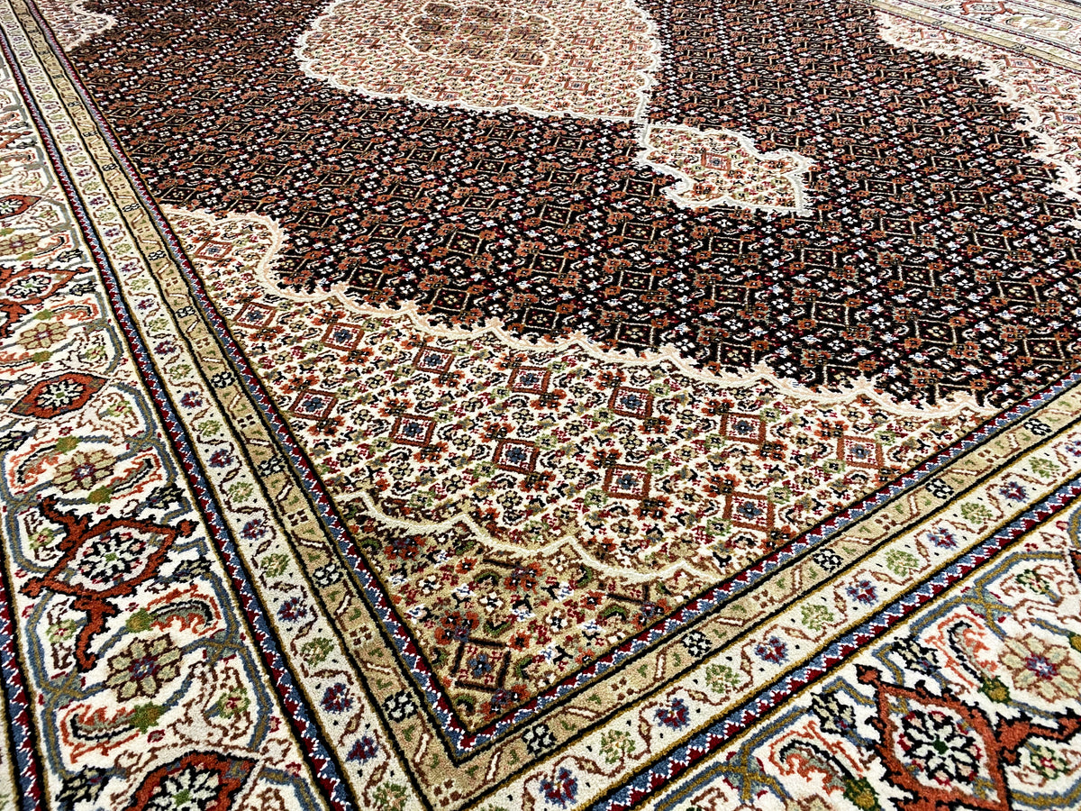 Primo piano di un tappeto Indo-Tabriz marrone: ornamenti del bordo e motivo floreale scuro