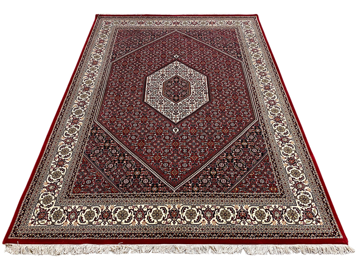 Tappeto rosso con medaglione centrale, ornamento simmetrico e frange sul bordo