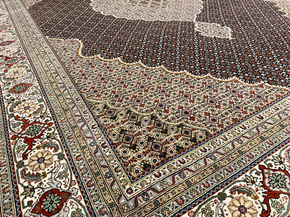 Angolo di un tappeto marrone scuro con bordo ornamentale e dettagli floreali