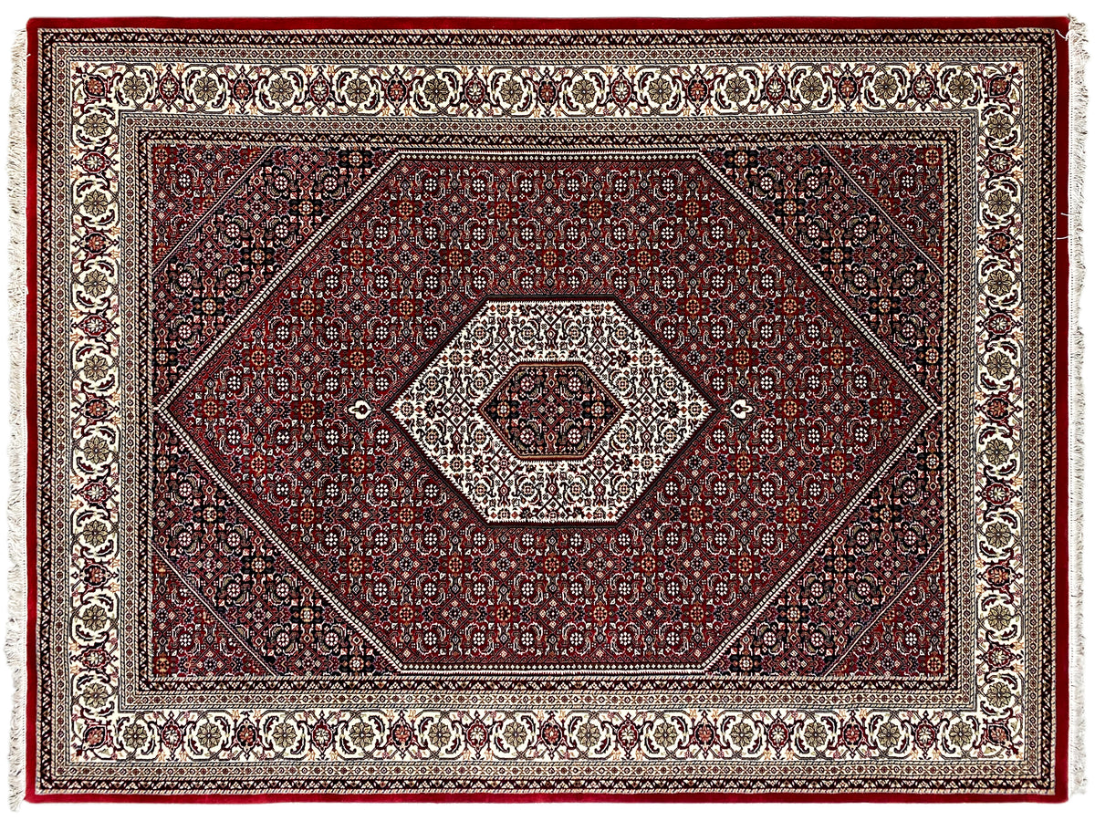 Primo piano del tappeto rosso: motivi a rombi e ornamentali con bordura decorativa, frange