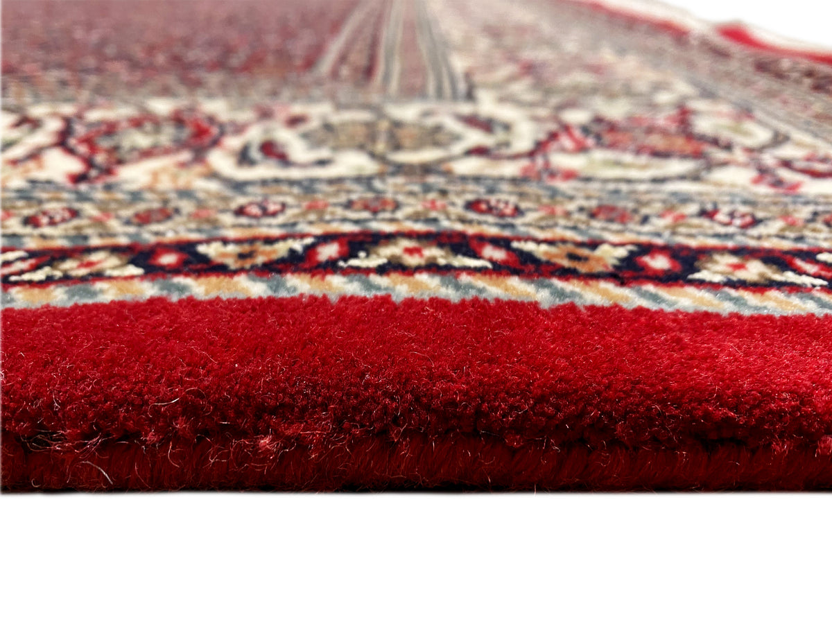 Primo piano della superficie del tappeto: pelo rosso e bordo decorato sul margine