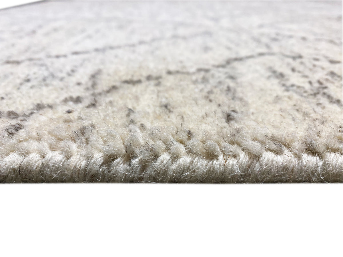 Primo piano del bordo del tappeto: pelo fitto color beige chiaro con motivo marezzato grigio