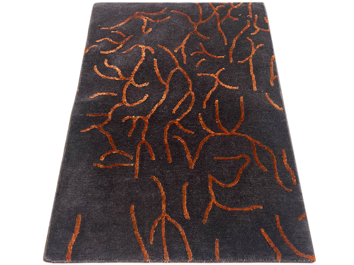 Tappeto rettangolare di design grigio scuro con motivo astratto arancione, inclinato