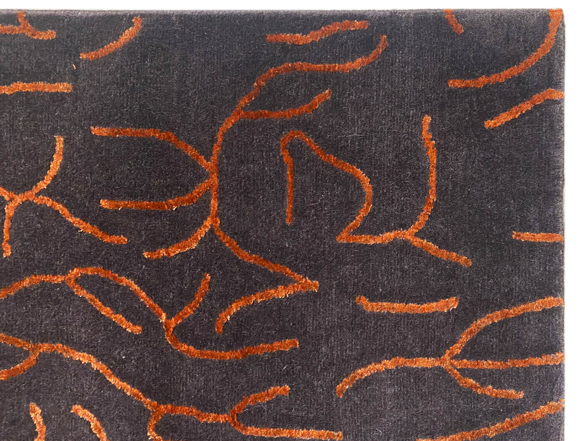 Vista ravvicinata di un tappeto di design: pelo grigio scuro con linee astratte arancioni