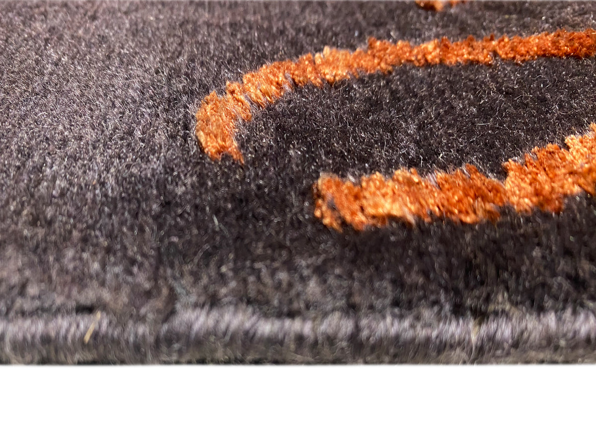 Dettaglio del tappeto: pelo grigio scuro con applicazioni arancioni a pelo alto