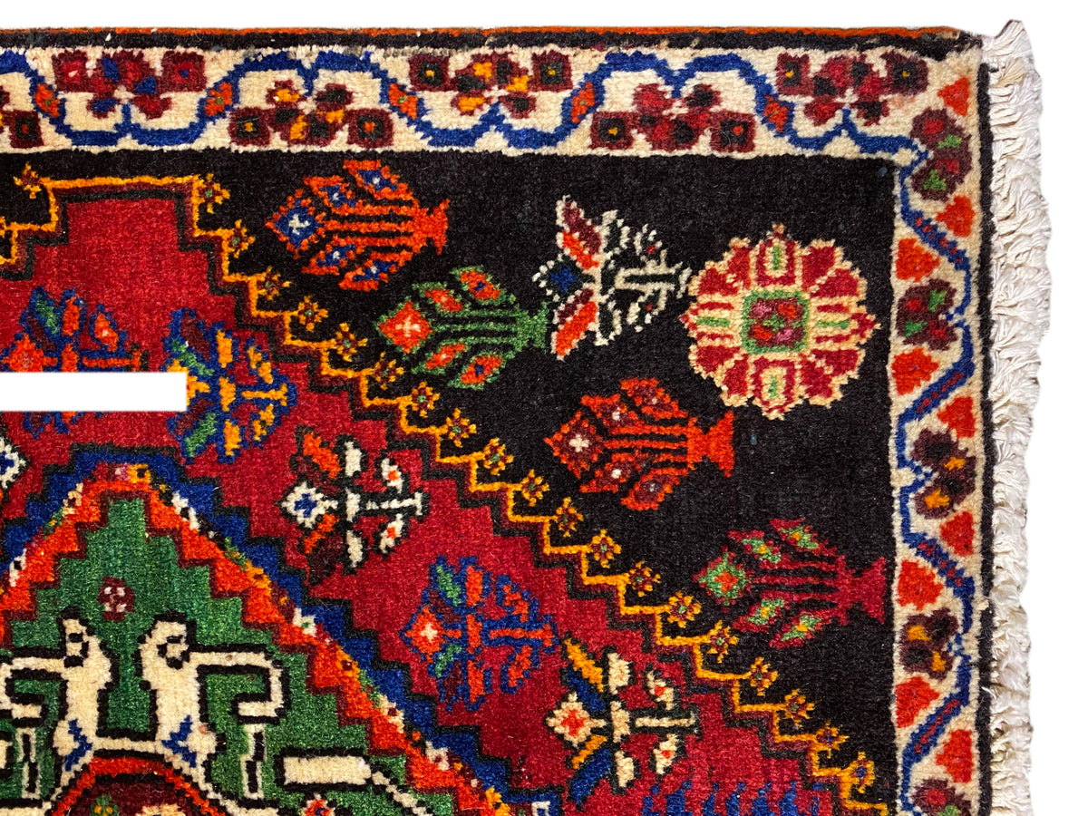 Tappeto Poshti 56x56 cm, vista ravvicinata: bordo ornamentale con rombi colorati su fondo nero
