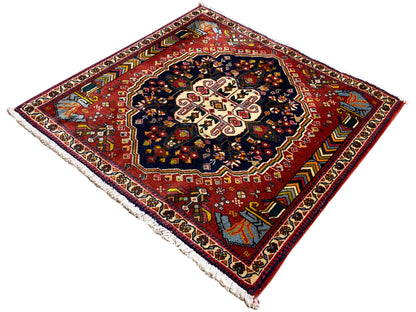Tappeto Poshti con fondo rosso, medaglione scuro e bordura perimetrale multicolore