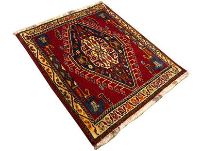 Tappeto Poshti (59×61 cm) disposto in diagonale, motivo geometrico rosso con frange