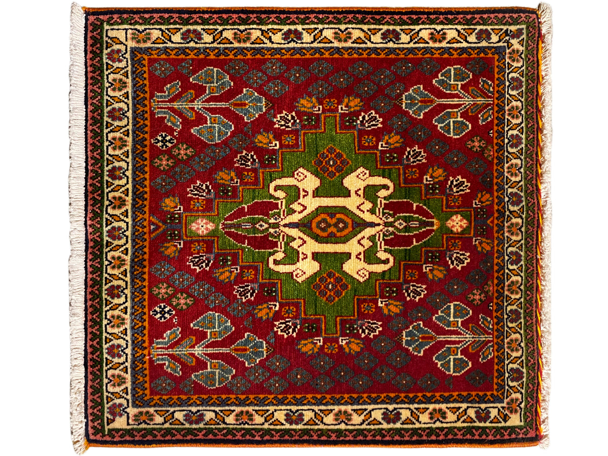 Tappeto orientale con fondo rosso, motivo a medaglioni verde e beige e bordo perimetrale, frange