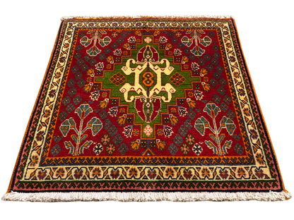 Tappeto orientale con motivo centrale rosso, dettagli verdi e bordo beige, con frange