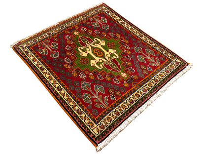 Tappeto orientale rosso con ornamenti a croce e a volute, accenti verdi e bordo decorativo