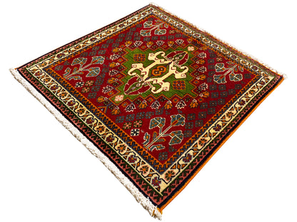 Tappeto orientale rosso con motivo centrale a croce, accenti verdi e bordo incorniciato
