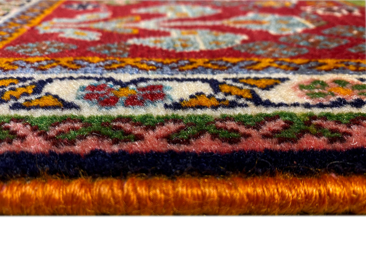 Bordo del tappeto nel dettaglio: pelo fitto con fondo rosso e ornamenti colorati