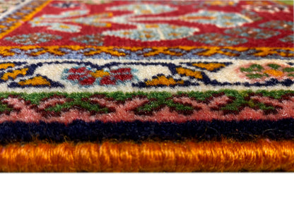 Bordo del tappeto nel dettaglio: pelo fitto con fondo rosso e ornamenti colorati