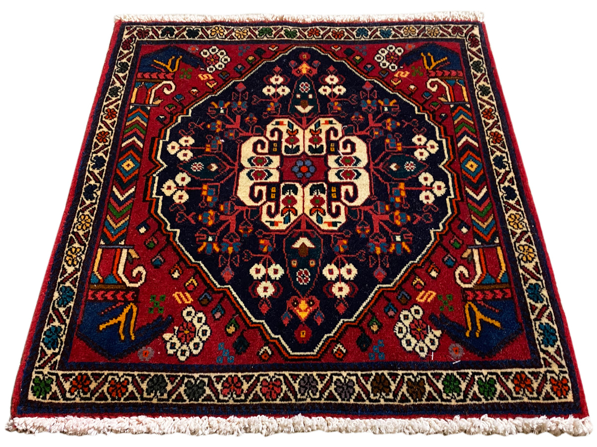 Tappeto quadrato con medaglione centrale, ornamenti rossi e blu e frange corte