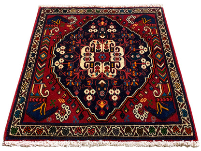 Tappeto quadrato con medaglione centrale, ornamenti rossi e blu e frange corte
