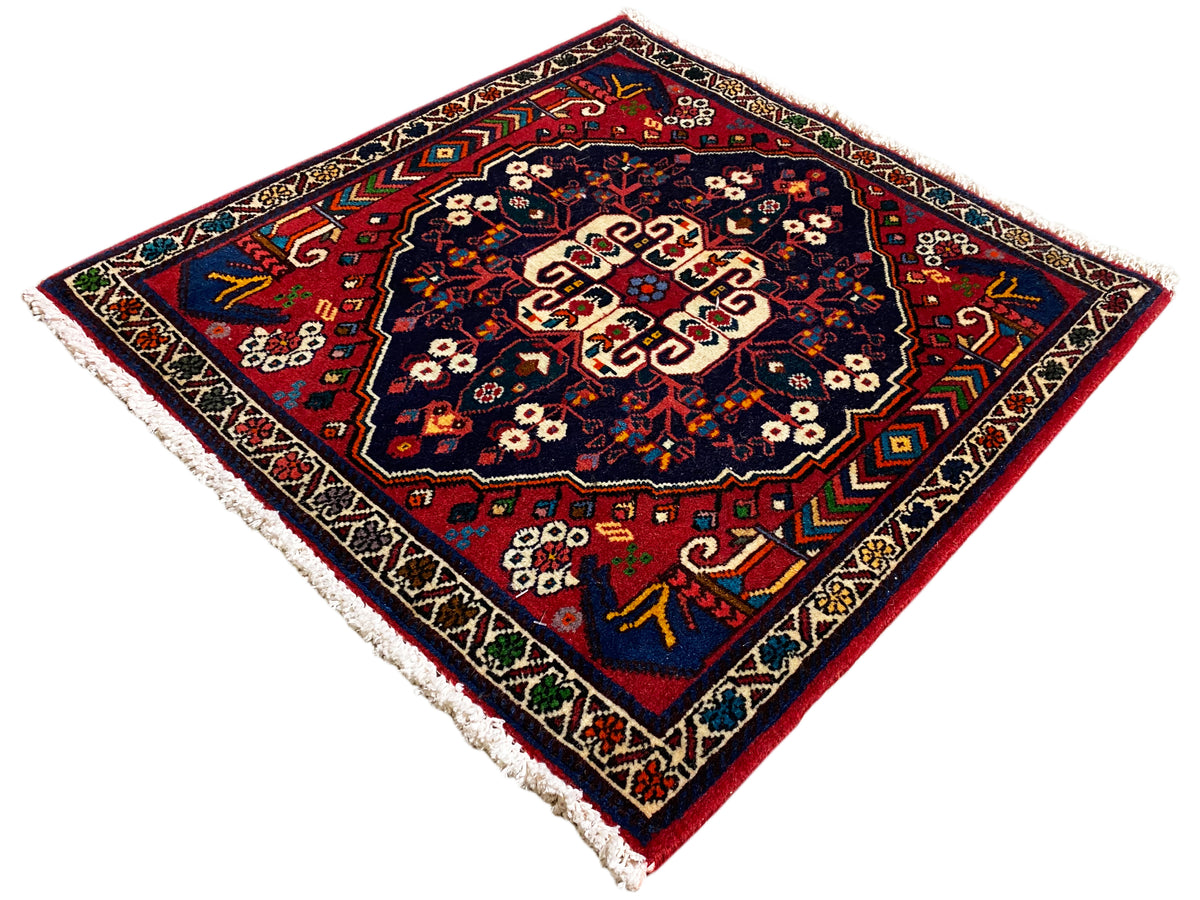 Tappeto quadrato con ornamento colorato, superficie blu intenso, motivi sul bordo, frange