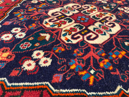 Vista ravvicinata del pelo del tappeto con motivi ornamentali colorati in blu, rosso, crema e verde