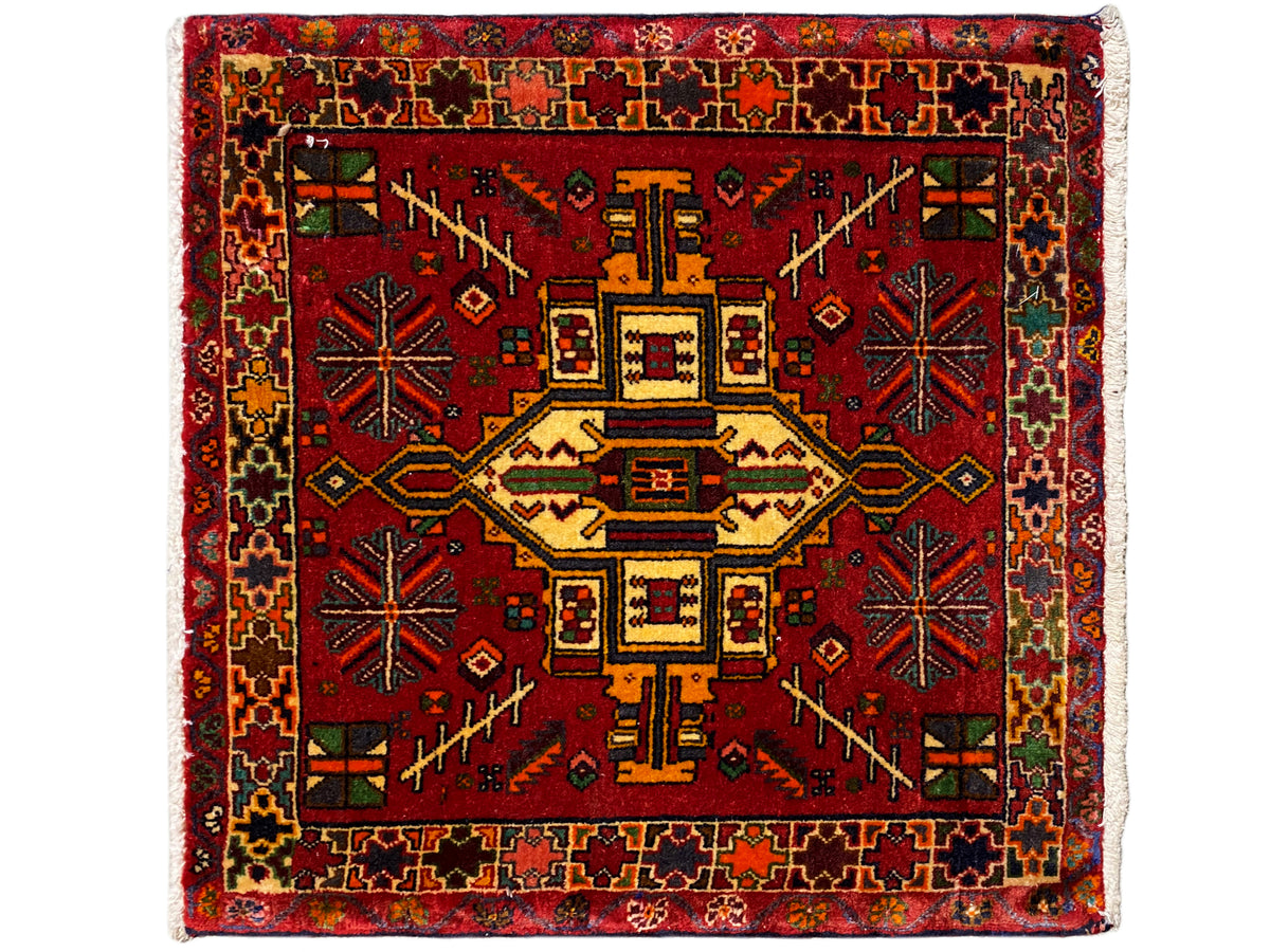 Tappeto Poshti rettangolare con sfondo rosso e motivo centrale geometrico multicolore