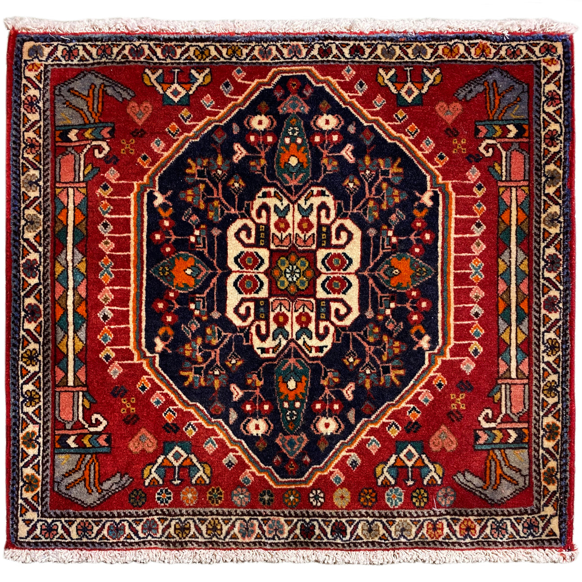 Tappeto quadrato con sfondo rosso e motivo centrale blu scuro, con frange