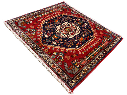 Tappeto a fondo rosso con medaglione centrale scuro, rettangolare, bordato con frange