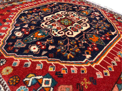 Superficie del tappeto: motivo ornamentale centrale su sfondo blu scuro, bordura colorata, bordo con frange