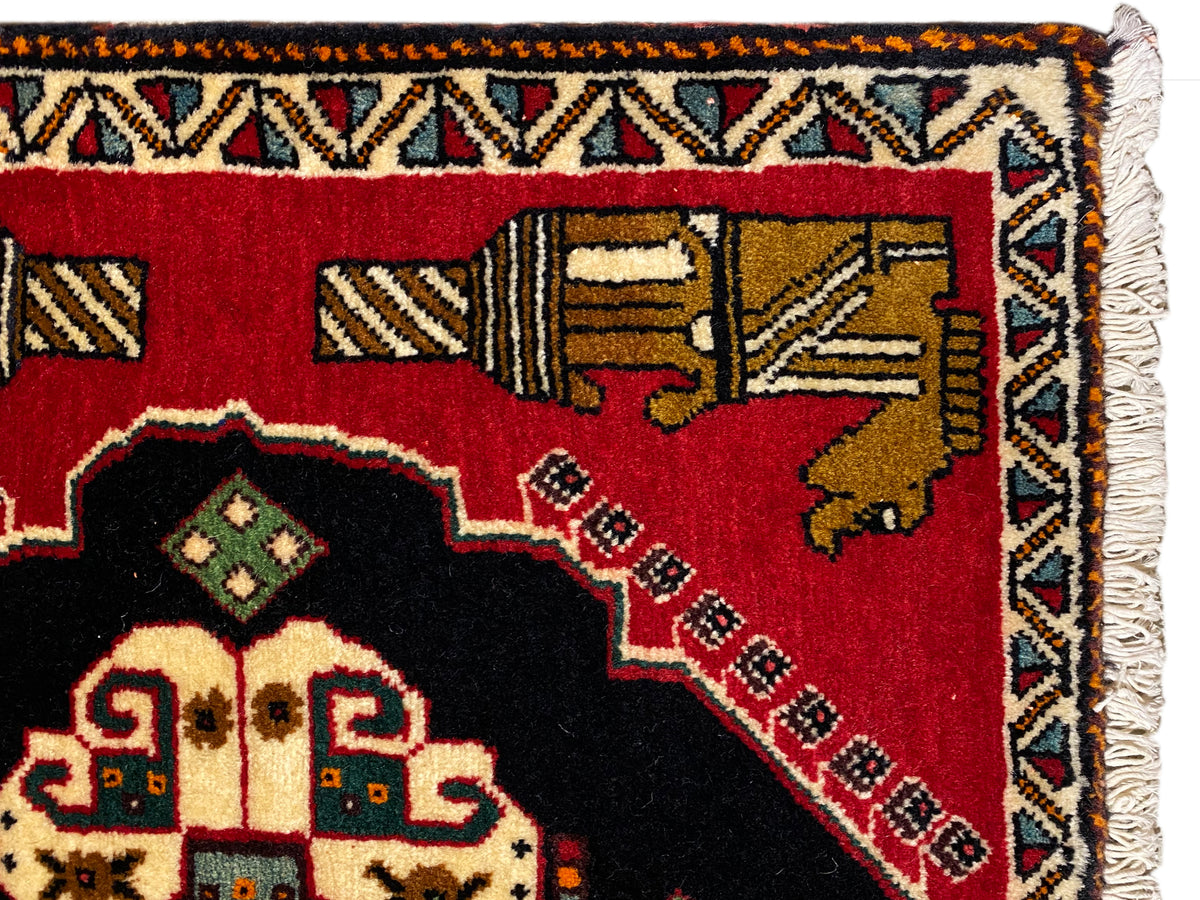 Tappeto Poshti 63x55 cm: dettaglio del bordo con frange e fascia ornamentale multicolore su fondo rosso