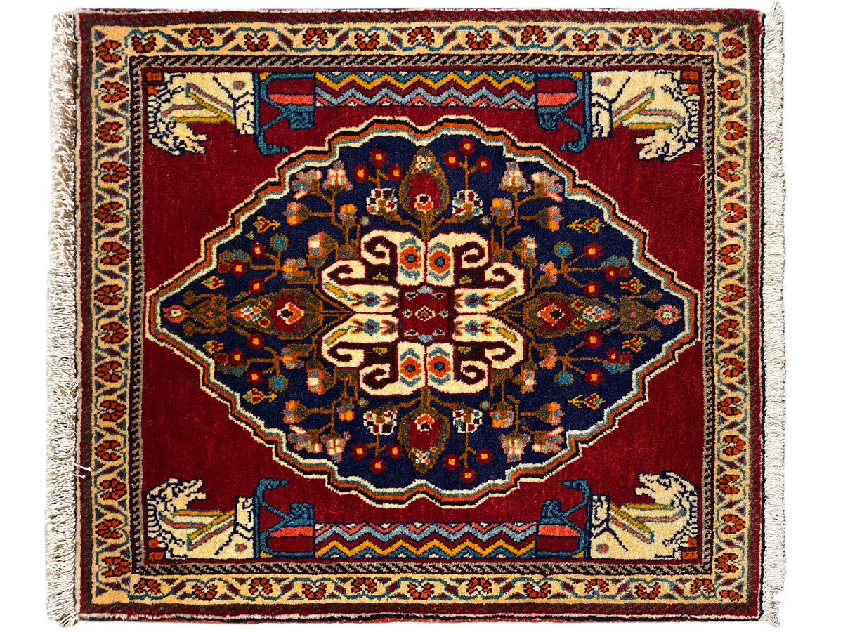 Tappeto rettangolare con fondo rosso, ornamenti blu scuro e bordature decorative beige