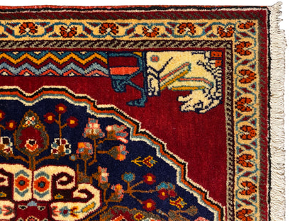 Vista dettagliata: motivo del tappeto rosso e blu scuro con elementi beige raffiguranti animali e figure