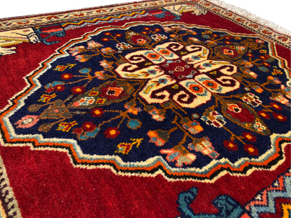 Primo piano del centro del tappeto: blu scuro, rosso, beige e superfici ornamentali multicolori