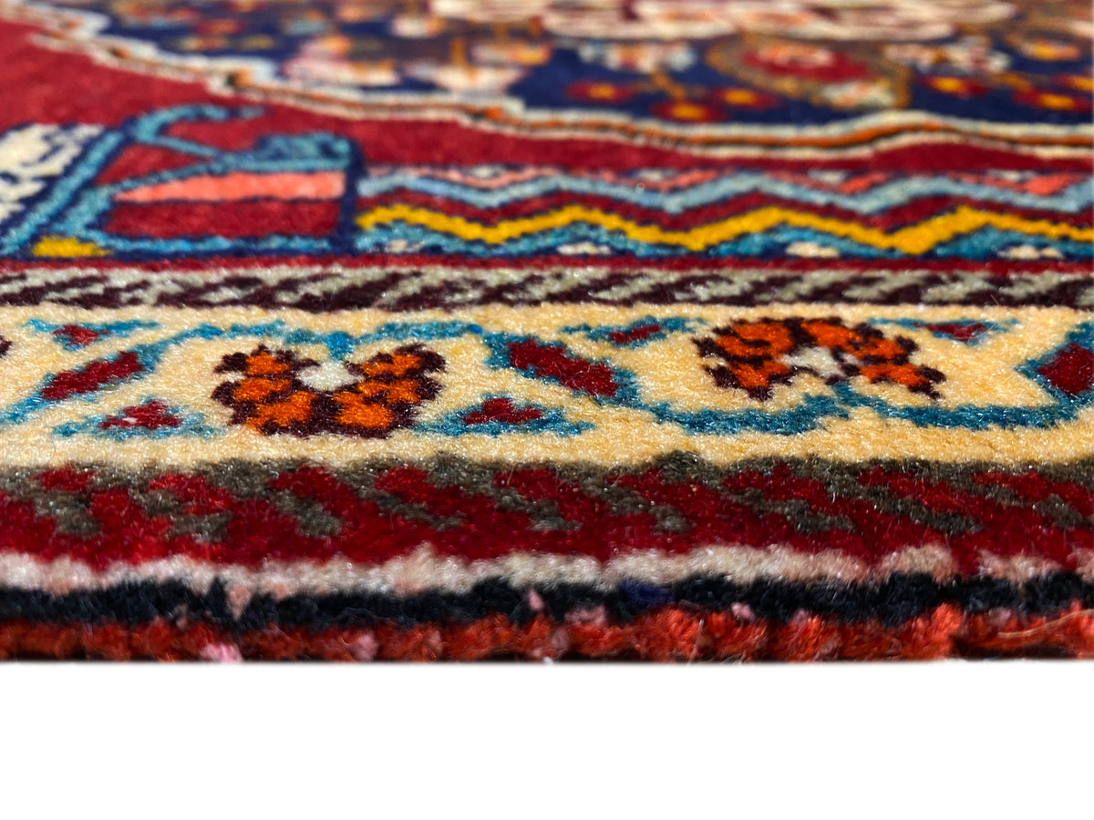 Dettaglio ravvicinato del tappeto: bordo colorato, ornamenti multicolori e folto vello annodato
