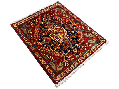 Tappeto 65x59 cm in vista ruotata: bordo rosso, motivi scuri, frange laterali