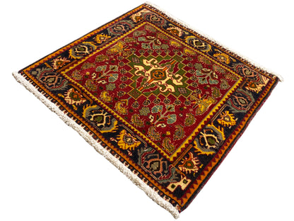 Angolo di tappeto con motivo rosso, accenti verdi e bordo decorativo scuro, frange