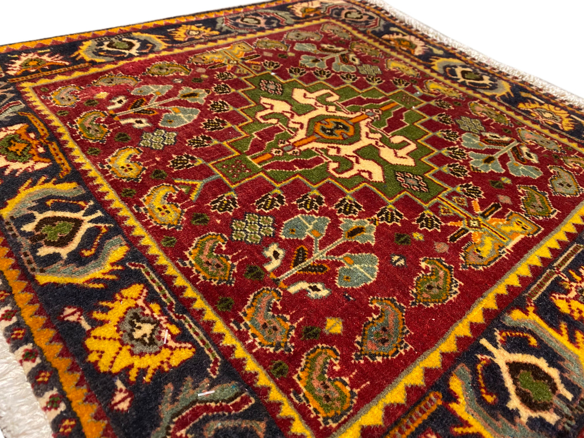 Superficie del tappeto con motivo centrale rosso, ornamenti verdi e bordo decorativo variopinto