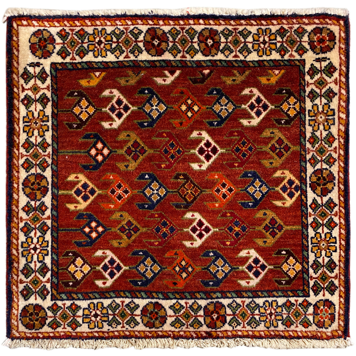 Tappeto quadrato con sfondo rosso, bordo variopinto bianco e frange