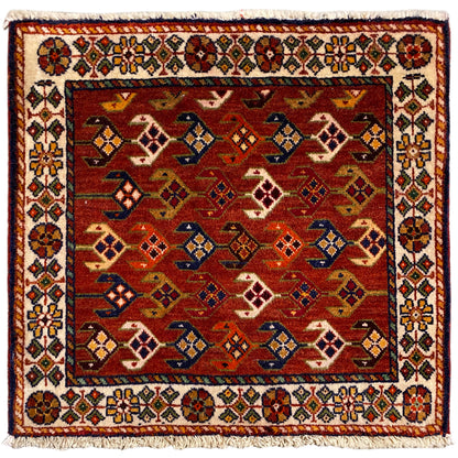 Tappeto quadrato con sfondo rosso, bordo variopinto bianco e frange