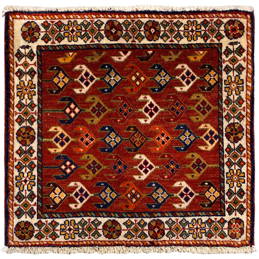 Tappeto quadrato con sfondo rosso, bordo variopinto bianco e frange