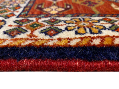 Bordo di tappeto con pelo rosso, bordo perimetrale scuro e fascia decorativa ornamentale