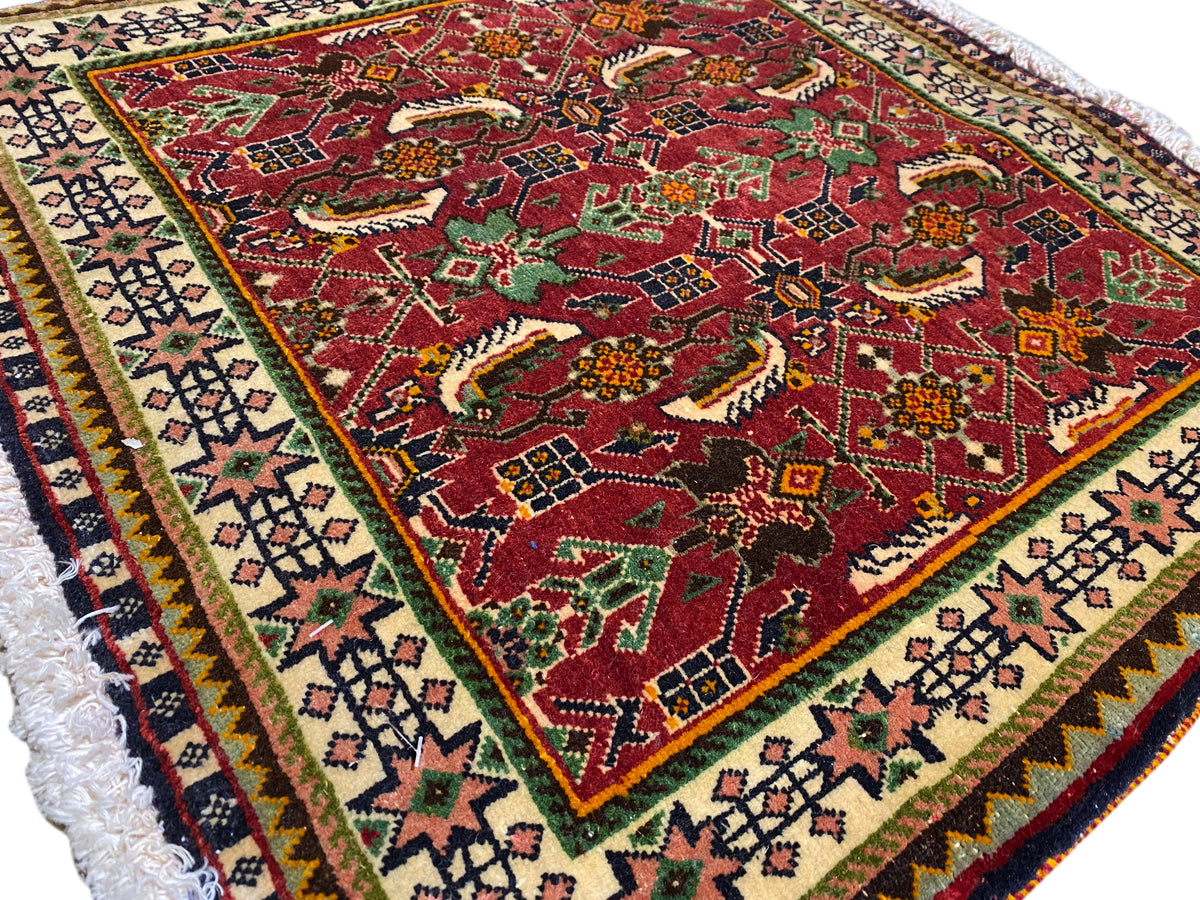 Tappeto Poshti 63x61 cm, vista dettagliata: motivo rosso con motivi animali/ornamentali e bordura.